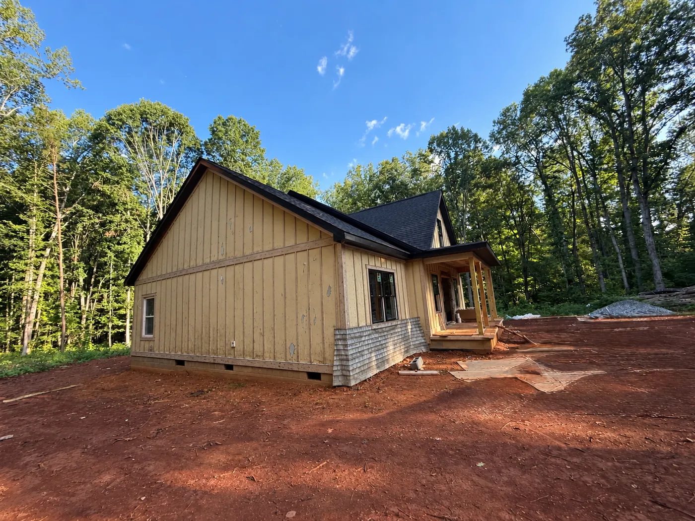 Before: a cabin with weathered beige siding and bare ground, surrounded by trees.