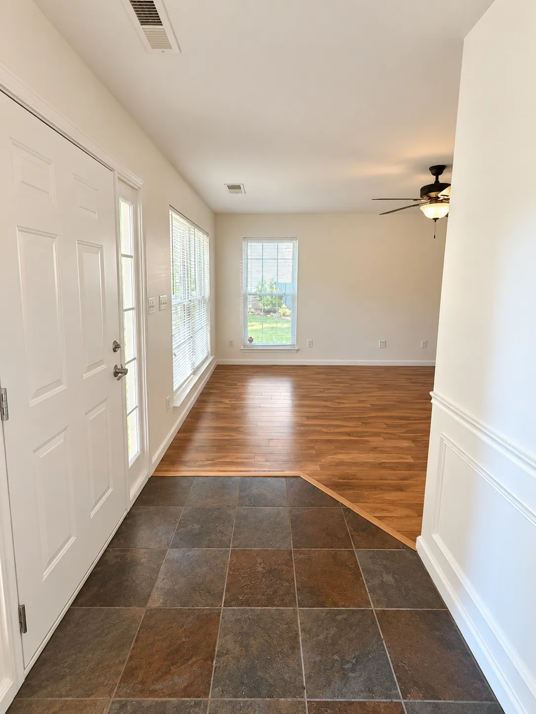 After: the same entryway with light neutral walls, white trim, and a warm ceiling fan light.
