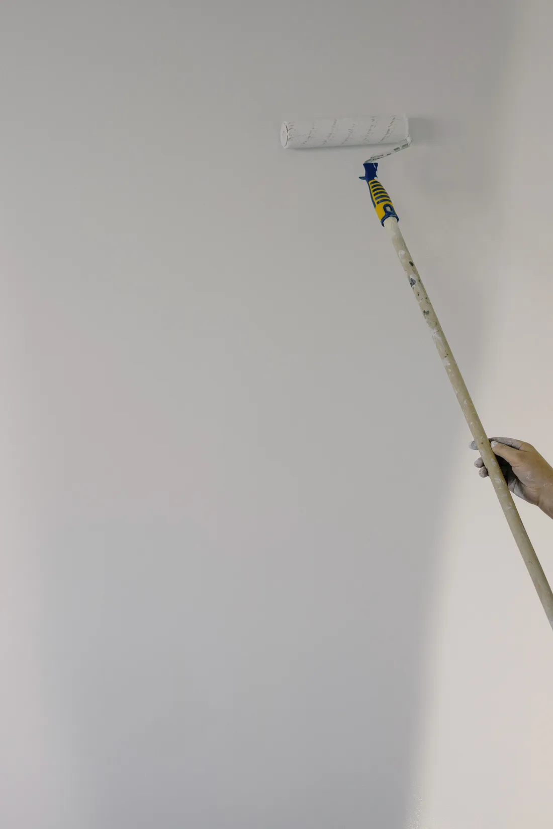 Stock photo: a painter rolling a white interior wall; not company work.